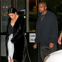Ada pula gaya streetwear Kim Kardashian mengenakan denim dengan cutout di lutut dan blouse hitam. Long coat juga cocok dipakai kencan saat malam hari. Foto: Dok. People