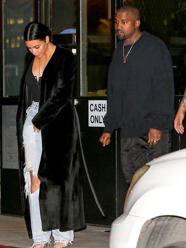 Ada pula gaya streetwear Kim Kardashian mengenakan denim dengan cutout di lutut dan blouse hitam. Long coat juga cocok dipakai kencan saat malam hari. Foto: Dok. People