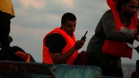 Seorang imigran Libya terlihat menggunakan telepon satelit dalam operasi penyelamatan ini 