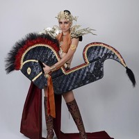 Sanjeda John sebagai perwakilan dari Malaysia dituding mencuri budaya Indonesia karena memakai kostum kuda lumping. Sanjeda John tampak memakai atasan cokelat dengan bagian perut terbuka. Dia juga memakai boots setinggi lutut. Penampilan seksinya ini ditutupinya dengan kuda lumping berukuran besar yang dipegangnya di depan perutnya. Foto: Dok. Instagram