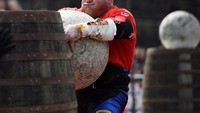 Kontes lainnya yaitu berlomba memasukkan batu berbentuk bola ke dalam drum kayu. Dilihat dari ekspresinya, bola batu itu sepertinya berat sekali (Clodagh Kilcoyne/Reuters)