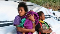 Seorang ibu dengan menggendong bayinya menanti proses evakuasi. REUTERS/Ben Bohane.