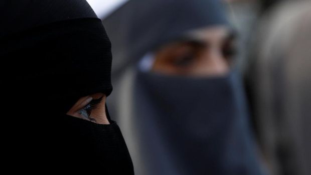 Demonstrators covering their faces participate in a protest called 