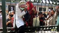 Penumpang berusaha keluar dari area rel kereta dengan menyelip di atas pagar besi.