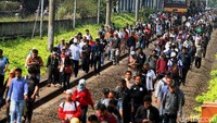 Rombongan penumpang menyelusuri rel kereta.