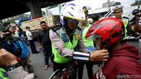 Seorang polisi bahkan membantu salah seorang pengendara sepeda motor untuk mengenakan helm dengan cara yang benar.
