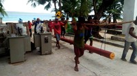 Petugas bahu-membahu membawa tiang listrik menuju desa di Maluku. (PLN).