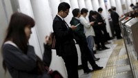 Orang-orang tampak ‘kompak’ memandang layar handphone saat menunggu kereta datang (REUTERS/Yuya Shino)