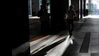 Seseorang berjalan cepat menuju salah satu gedung (REUTERS/Toru Hanai)