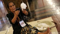 Seorang perajin menyiapkan bahan berupa kapas untuk pembuatan kain tenun.