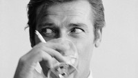 Aktor Inggris, Roger Moore minum Martini, gaya yang khas dengan James Bond. Foto ini diambil pada 17 Juli 1968. Foto: Peter Ruck/BIPs/Getty Images
