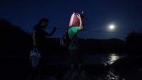 Warga lokal mengangkut satu jeriken bensin ketika menyeberang sungai menggunakan kabel setelah Badai Maria meruntuhkan jembatan kota di San Lorenzi, Morovis, Puerto Riko (Foto: REUTERS/Alvin Baez)