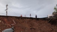 Beberapa warga lokal Barranquitas, Puerto Rico, berdiri di dekat jalanan yang hancur akibat serangan badai Maria. (Foto: REUTERS/Alvin Baez)