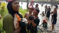 Seorang ibu memeluk erat ikan hasil tangkapannya agar tak terlepas