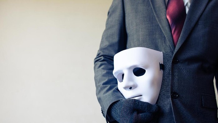 Business man carrying white mask to his body indicating Business fraud and faking business partnership
