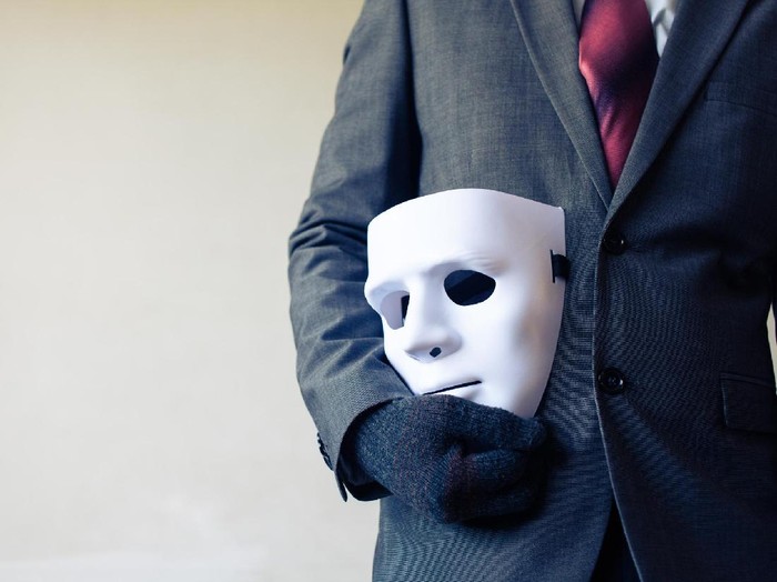 Business man carrying white mask to his body indicating Business fraud and faking business partnership