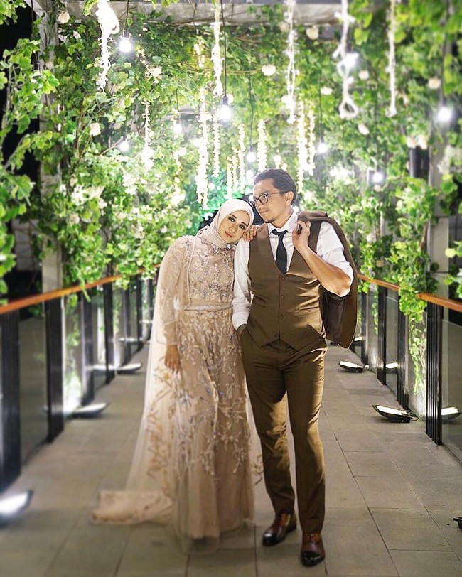 Laudya Cynthia Bella mengenakan gaun pengantin berupa jumpsuit dengan sentuhan dusty pink yang elegan saat menggelar resepsi pernikahannya bersama Engku Emran di Bandung, Jawa Barat. Baju pengantin tak biasa yang berupa jumpsuit tersebut dibuat oleh desainer busana muslim Ayu Dyah Andari. Foto: Dok. Instagram