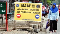 Seorang warga melintas di sisi jalan saat pengerjaan pedestrian.