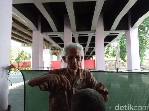 Tangan H.Maksum cekatan memotong rambut pelanggan/