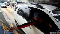 Seorang pengendara meletakan kartu e-Toll pada mesin di gerbang tol.