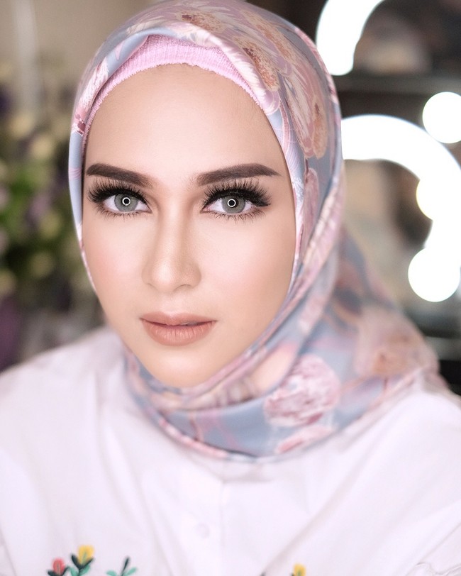 Nina Zatulini tampil cantik mengenakan ciput rajut anti pusing saat memakai jilbab satin. Kali ini penampilannya terlihat beda dengan wajah penuh riasan.  Foto: Dok. Instagram