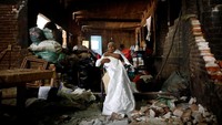 Justina Escamilla, 88, memegang gaun pengantinnya di dalam rumah yang rusak akibat gempa yang mengguncang di San Juan Pilcaya. Foto diambil pada 25 September 2017 lalu. Lokasi ini temasuk pusat gempa di Meksiko. (REUTERS/Edgard Garrido)