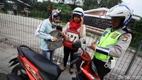 Polisi memeriksa kelengkapan surat-surat pengendara sepeda motor.
