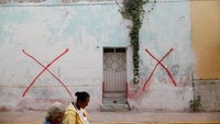 Perempuan berjalan melewati rumah bertanda X di Tepalcingo, Tanda ini dicantumkan di rumah-rumah yang mengalami kerusakan parah akibat gempa bumi. Rumah yang bertanda X harus dirubuhkan. (REUTERS/Edgard Garrido)