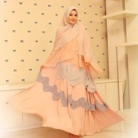 Bagaimana dengan penampilan Lyra Virna ketika memakai gamis panjang dan khimar sifon berwana peach ini? Ia menggunakan teknik aplikasi gelombang pada tempelan busana depannnya. Khimarnya juga pilih yang memiliki permainan teknik layering. Foto: Dok. Instagram @lyravirna
