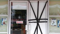 Tampak kaca pintu perpustakaan pecah. Pintu tersebut kemudian ditutup menggunakan papan dan dilakban
