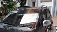 Di samping gedung juga terparkir mobil hitam yang sebagian kacanya tertutup sisa-sisa tanah dari pot tanaman.