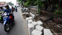 Pengendara sepeda motor melintas di depan proyek pembangunan trotoar di Jalan Dewi Sartika, Jakarta Timur.