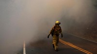 Petugas pemadam kebakaran harus menembus tebalnya asap untuk menuju titik api. Jim Urquhart/Reuters.