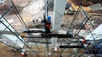 Seorang pekerja menyiapkan tangga untuk merenovasi stadion.