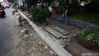 Dua orang warga melintas di lokasi proyek pembangunan trotoar.