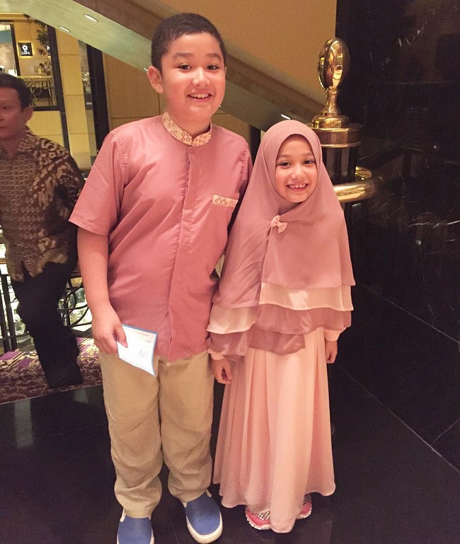 Eisha bergaya kompak dengan sang kakak, Queizal Mirosyavir Ali Bachmid. Ia didandani memakai gamis pink panjang dan khimar berlayer. Tambahan pita kecil membuat Eisha semakin imut. Foto: Dok. Instagram @lyravirna
