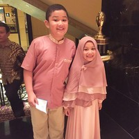 Eisha bergaya kompak dengan sang kakak, Queizal Mirosyavir Ali Bachmid. Ia didandani memakai gamis pink panjang dan khimar berlayer. Tambahan pita kecil membuat Eisha semakin imut. Foto: Dok. Instagram @lyravirna