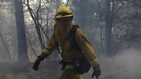 Tebalnya asap memaksa petugas menggunakan masker untuk mencapai sumber api. Jim Urquhart/Reuters.