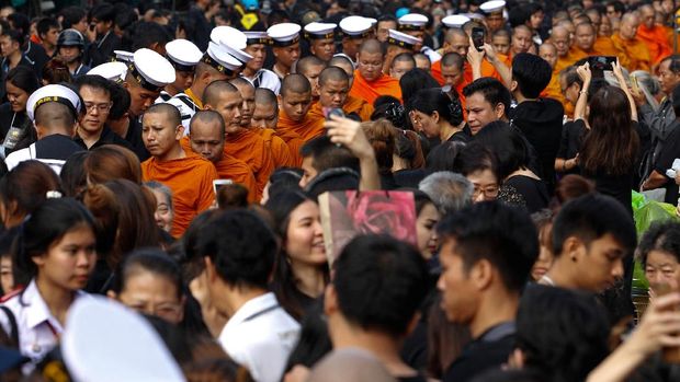 Warga yang masih berkabung memberikan sedekah kepada para biksu