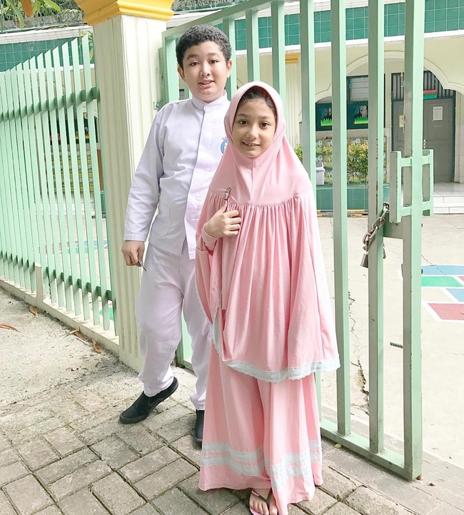 Kali ini Eisha tampil manis mengenakan hijab syari warna merah muda. Sentuhan renda putih pada bagian bawah gamis dan khimarnya membuat penampilan terlihat segar.  Foto: Dok. Instagram @lyravirna