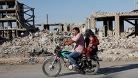 Warga menggunakan sepeda motor melewati bangunan yang hancur di Kobani (Dok. REUTERS/Erik De Castro)