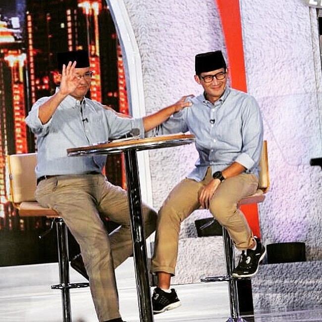 Tampil kompak dengan paduan kemeja biru muda dan celana warna khaki, masing-masing tampil dengan gaya berbeda. Anies terkesan formal dengan kemeja yang dimasukkan ke celana dan sepatu kulitnya, sementara Sandi berusaha tampil kekinian dengan menggulung celana dan memakai sneakers monokrom sebagai padanan. Foto: Dok. Instagram