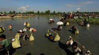 Para pengungsi menyebrangi sungai. Zohra Bensemra/Reuters.