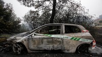 Sebuah mobil terongok di tepi hutan setelah ludes dimakan api. Miguel Vidal/Reuters.