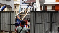 Rumah bercat abu-abu yang tertimpa tiang LRT rusak di bagian atap.