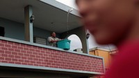Ia menadah air hujan dengan ember di tangannya (Dok. REUTERS/Alvin Baez)