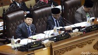 Novanto duduk di samping Agus Hermanto. Novanto terlihat mengenakan jas dan memakai peci hitam.
