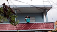 Seorang pria menampung air hujan yang mengalir melalui saluran air di rumahnya di Toa Baja, Puerto Rico. (Dok. REUTERS/Alvin Baez)