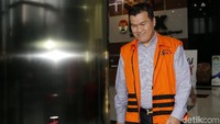 Andi Narogong berjalan meninggalkan gedung KPK sambil melempar senyuman.