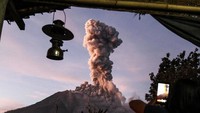 Seorang warga desa memotret kepulan asap tebal dari Gunung Sinabung. Pemandangan ini dipotret dari Desa Tiga Pancur di Karo (Foto: AFP/Getty Images)